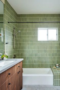 a bathroom with green tiles on the walls and floor, along with a bathtub