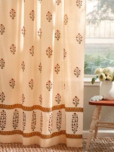 a white curtain with red and green designs hanging from it's side in front of a window