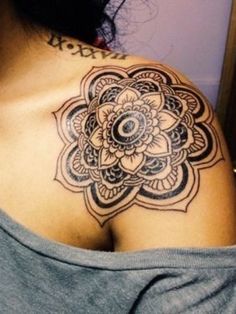 a woman with a tattoo on her shoulder has a flower design on the back of her shoulder