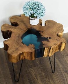 a table made out of wood and metal legs with a vase filled with flowers on top