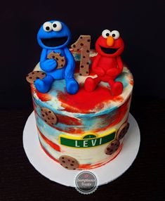 the birthday cake is decorated with an elmo and cookie monster number one on top