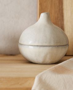 a white vase sitting on top of a wooden table