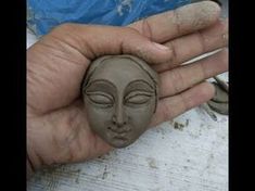 a person holding a clay face in their hand