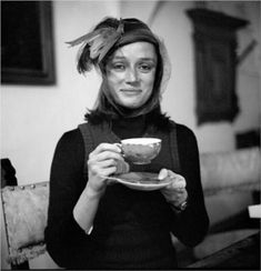 black and white photograph of a woman holding a tea cup in her hands with feathers on it