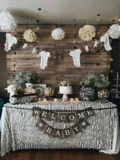 a welcome baby sign is hanging from the wall next to a table covered in decorations