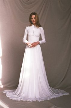 a woman in a white dress is standing with her hands on her hips