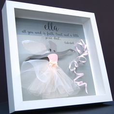 a white frame with some pink and white items in it's display case that says, ella all you need is fabric ribbon and a little piece of tulle