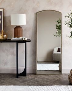 a living room with a mirror, lamp and vase on the table in front of it