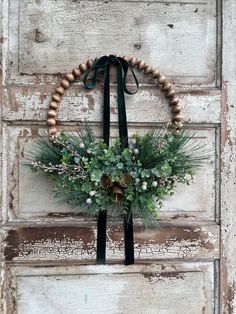 a wreath with pine cones and greenery hangs on an old door