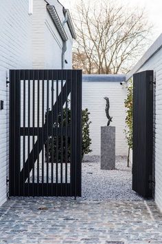 an open gate leading into a courtyard with a statue in the center and black iron gates on either side