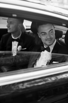 two men in tuxedos are sitting in a car