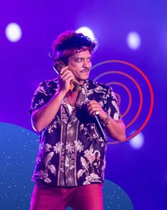 a man standing in front of a microphone on top of a purple and blue stage