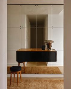 a black table and stool in front of a mirror wall with mirrored doors on it