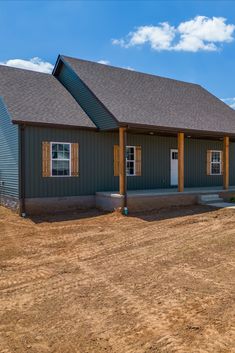 a large gray house sitting on top of a dirt field