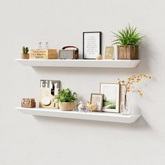 two white shelves with plants and pictures on them