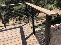 a wooden deck with metal railing and sheep in the background