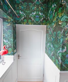 an open door in a room with green wallpaper and flamingos on the walls