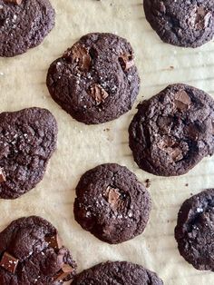 chocolate cookies are lined up on a piece of parchment paper and ready to be eaten