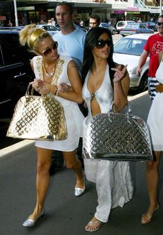 two women walking down the street carrying purses