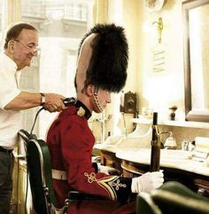 a man in uniform cutting another mans hair