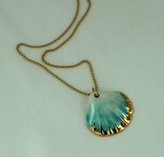 a gold chain with a blue pendant hanging from it's end on a white surface