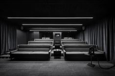 a black and white photo of an empty movie theater with two recliners in front of the seats