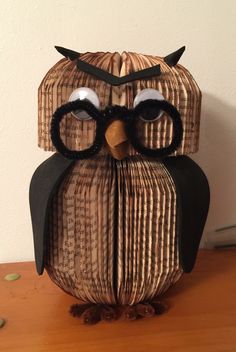 an origami owl sitting on top of a wooden table next to a wall