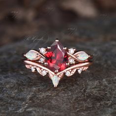 a close up of a ring with a red stone in the center on a rock