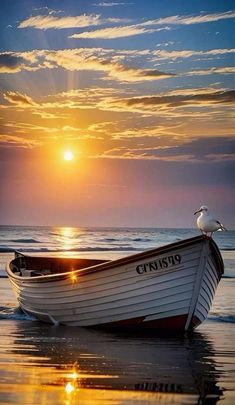 a boat sitting on top of a beach next to the ocean under a cloudy sky