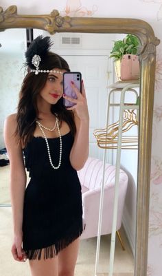 a woman taking a selfie in front of a mirror wearing a black flap dress