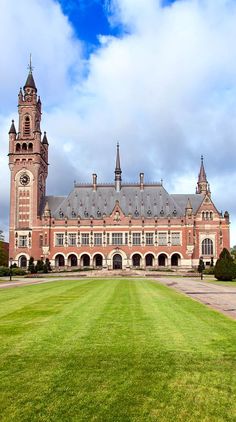 a large building with a clock tower on top of it's roof and grass in front of it