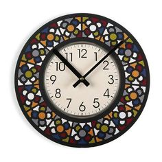 a clock that is on the wall with numbers and circles around it, all painted in different colors