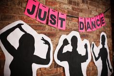 some pink and black stickers are hanging on a brick wall next to a sign that says just dance