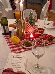 a table topped with wine glasses and plates filled with food next to bottles of wine