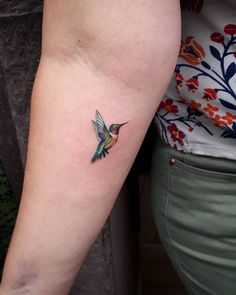 a small hummingbird tattoo on the arm