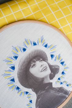 an embroidered picture of a woman's face on a yellow and white table cloth