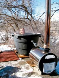 a man sitting in a hot tub on top of a wooden deck next to a tree