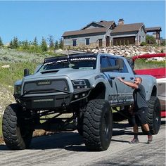 a man standing next to a monster truck on the road in front of a house