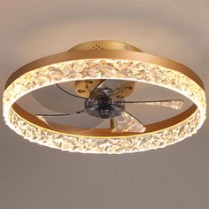 a ceiling fan that is lit up with lights on top of it and an intricate design around the blades