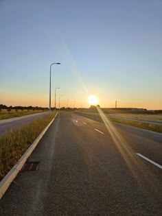 the sun is setting on an empty highway