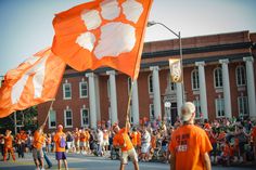 an orange and white flag is being held in front of a building with people watching