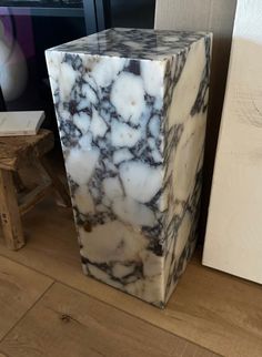 a marble block sitting on top of a wooden floor next to a white box with black and gray designs