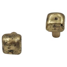 two gold colored knobs are shown against a white background and one has black spots on it