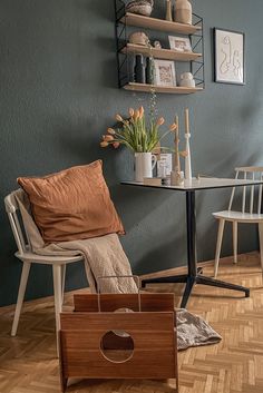 a chair and table in a room with wood flooring next to a blue wall