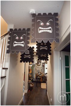 two black and white paper cut outs with faces on them hanging from the ceiling in a hallway