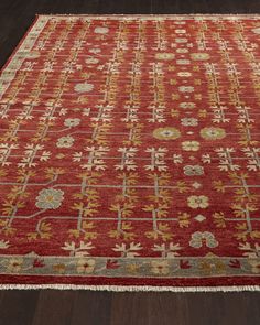 a red rug with gold and white designs on the bottom is sitting on a wooden floor