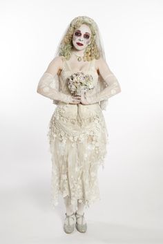 a woman dressed as the bride with makeup on her face and dress is holding a bouquet