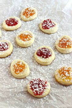 cookies with jam and powdered sugar are arranged on a baking sheet, ready to be baked