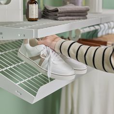 a person is trying to put their shoes on the shelf