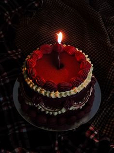 a red heart shaped cake with a lit candle